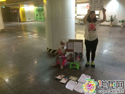 今日下午,重庆两路口轻轨站,陈得娟举着牌子,女儿则坐在她的身边。 实习记者 艾俊锋 摄 今日下午,重庆两路口轻轨站,陈得娟举着牌子,女儿则坐在她的身边。 实习记者 艾俊锋 摄